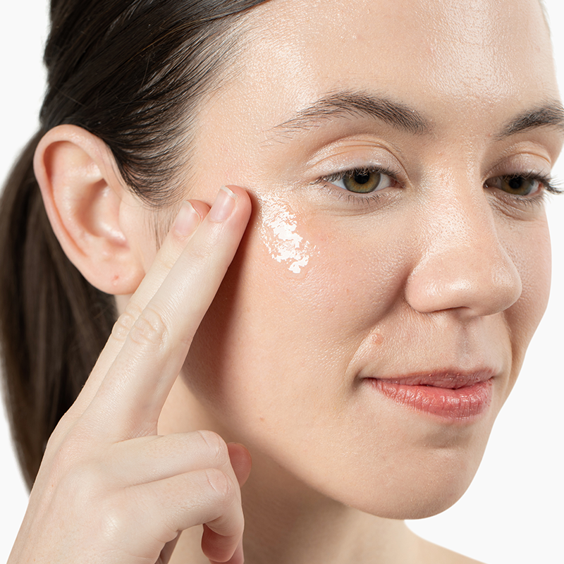 Woman applying Vivian Valenty Skincare cleanser to her cheek for a fresh, healthy glow.