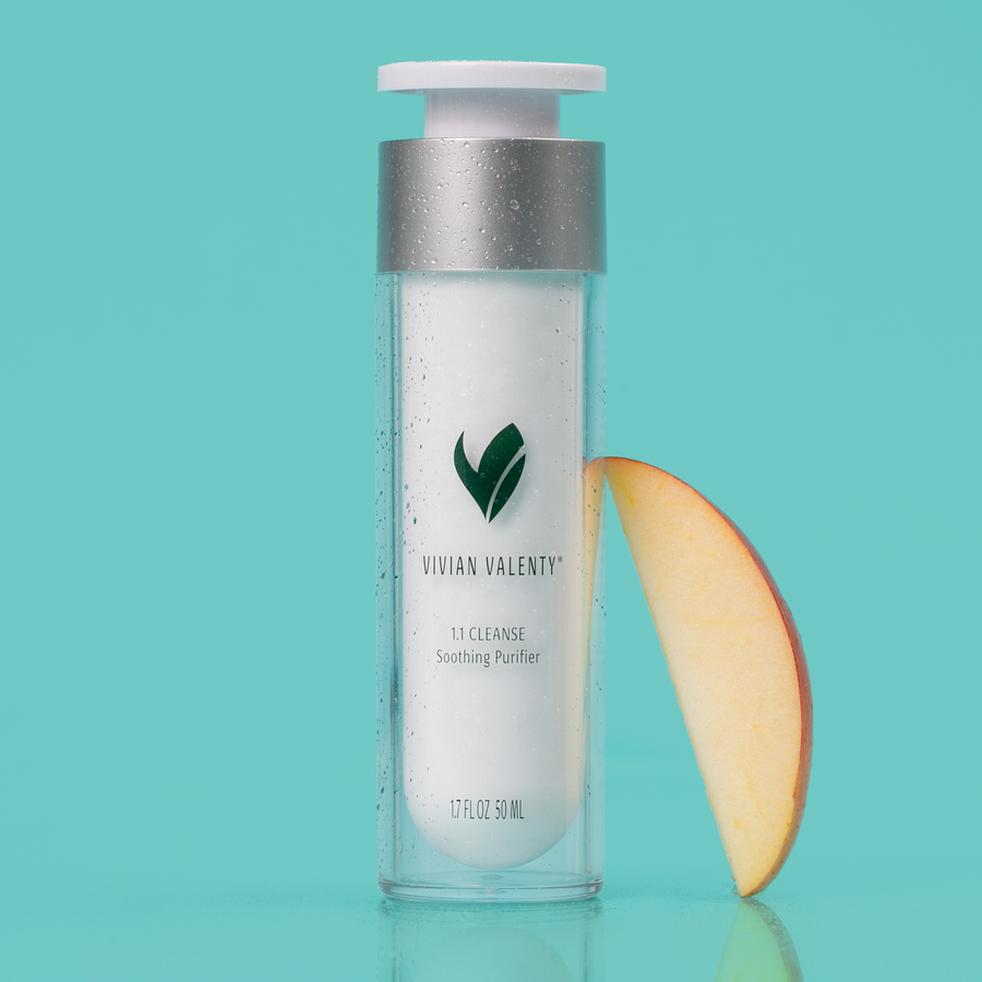 Step 1: Vivian Valenty Skincare 1.1 Cleanser on a turquoise background with water droplets and a fresh apple, representing clean, fresh, and healthy skin.