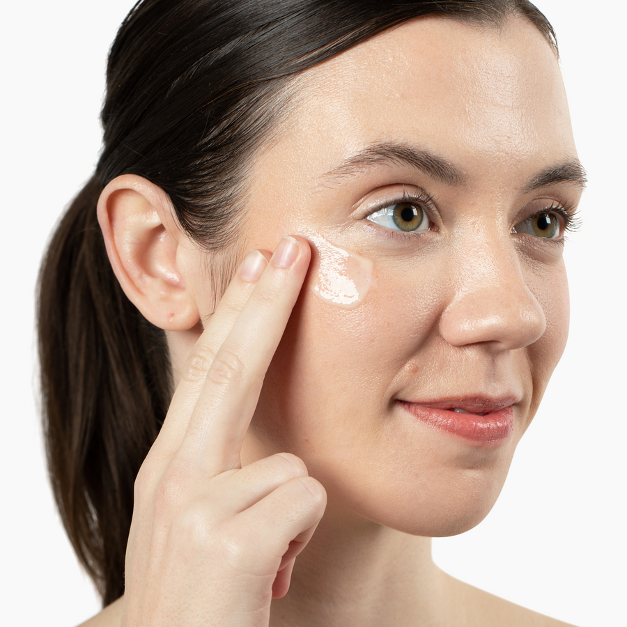 Woman applying Vivian Valenty Skincare cleanser to her cheek for a fresh, healthy glow.